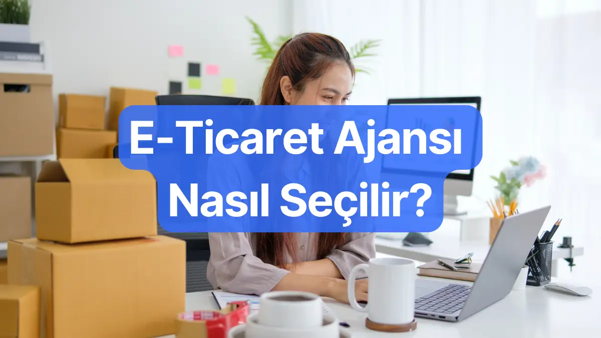 E-ticaret ajansı nasıl seçilir kapak görseli, kargo kolilerinin önünde dizüstü bilgisayarında çalışan bir e-ticaret yöneticisi